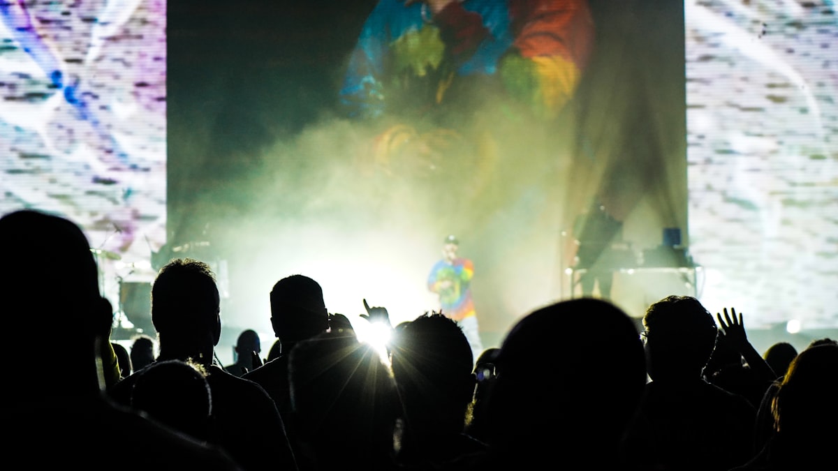 Foule en concert la nuit, mains levées vers la scène
